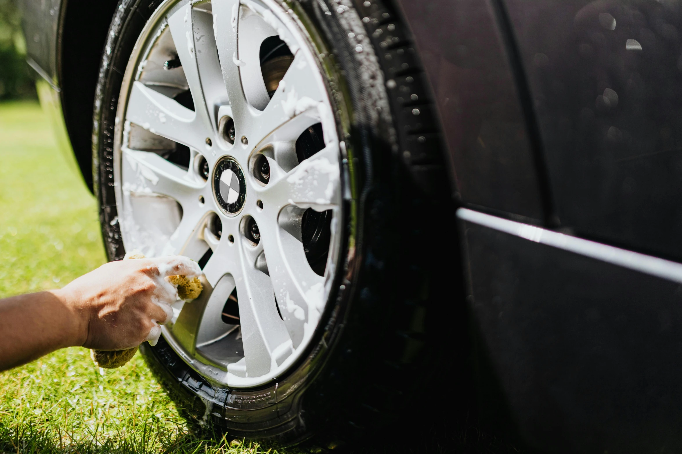 someone cleaning and waxing a tire on a car