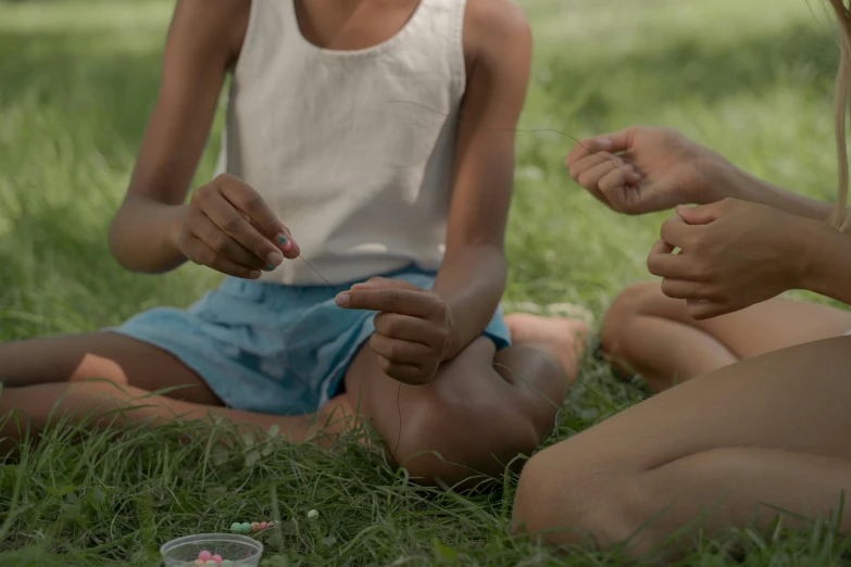 two girls sitting on the grass putting soing in their hands