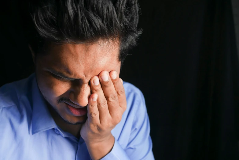 a young man is standing with his head in his hands