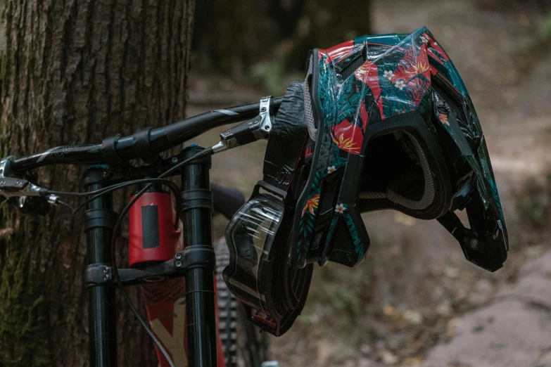 a bicycle parked next to a tree on the side of a trail