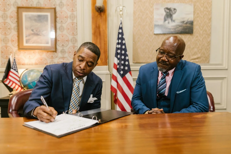 two people sitting at a table signing paperwork