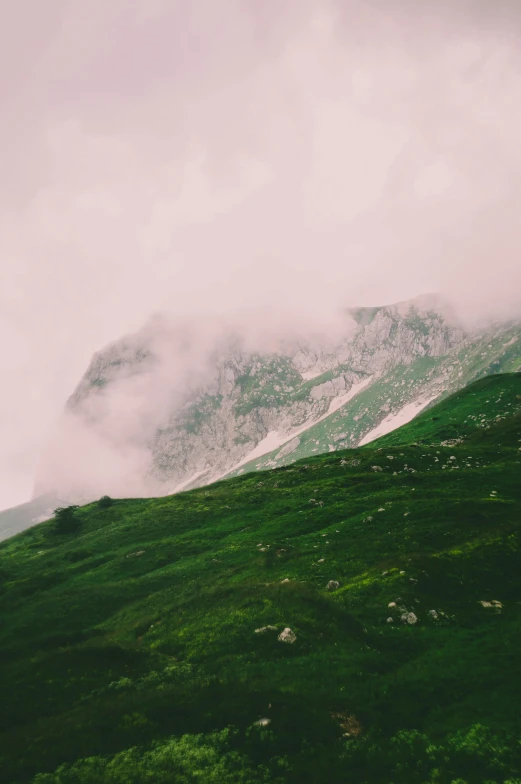 green mountain with snow on top in the clouds