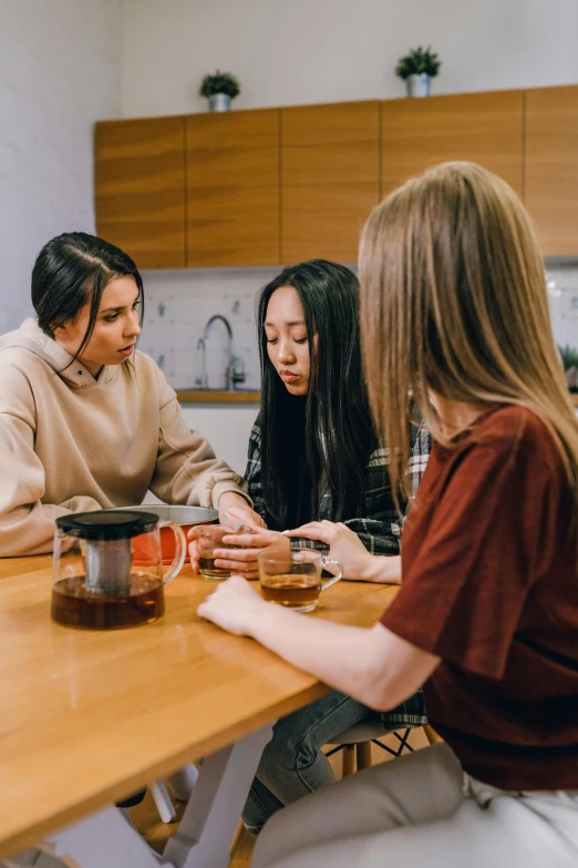 three women having a conversation around a wooden table