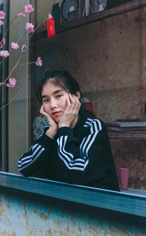 a person sits behind a window near a bush