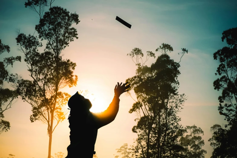 person in front of the sun holding up soing to fly