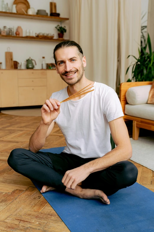 a man is sitting on a yoga mat and smiling