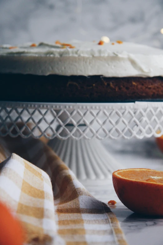 a cake on top of a white stand with an orange next to it