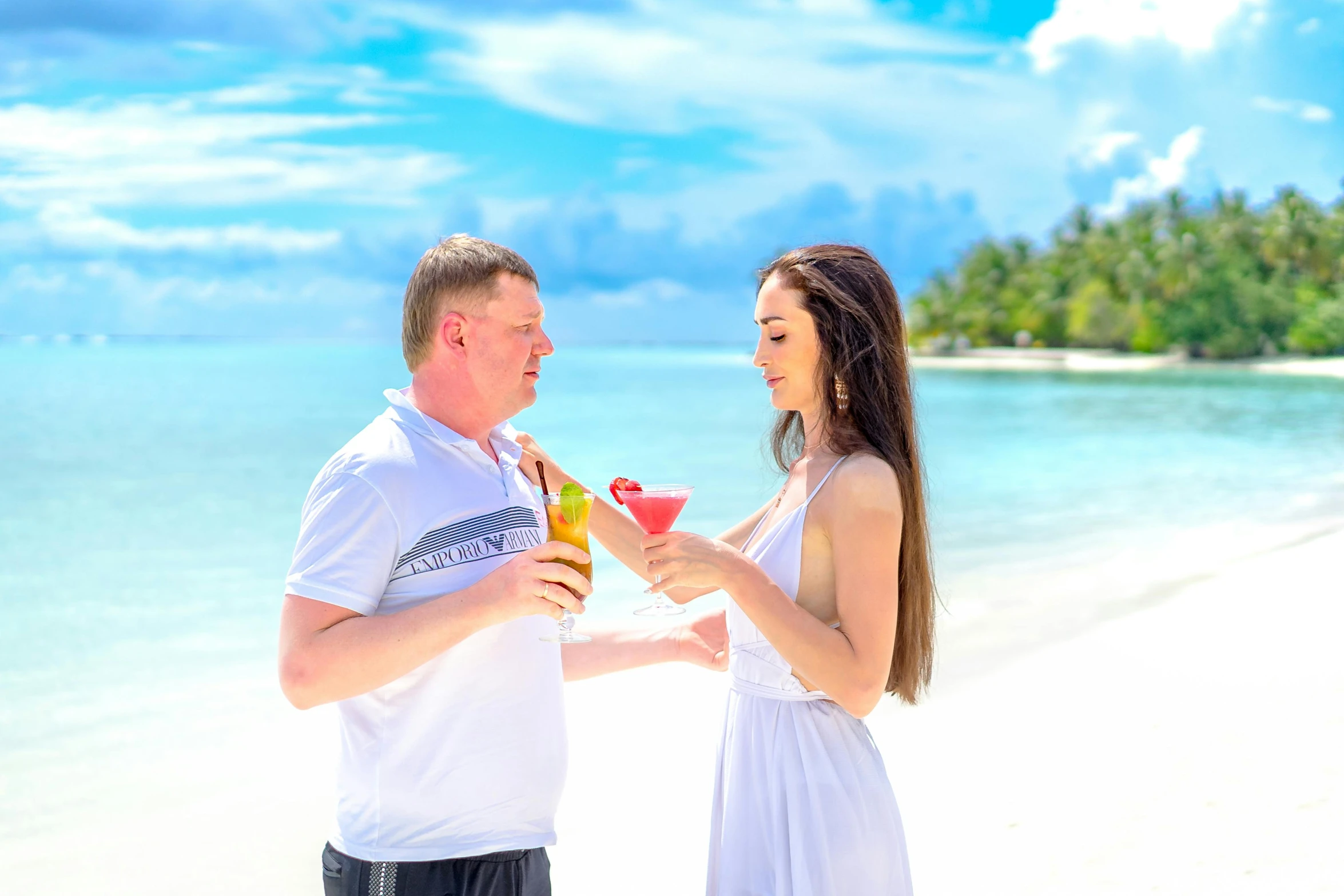 a man and woman are on the beach and drink cocktails