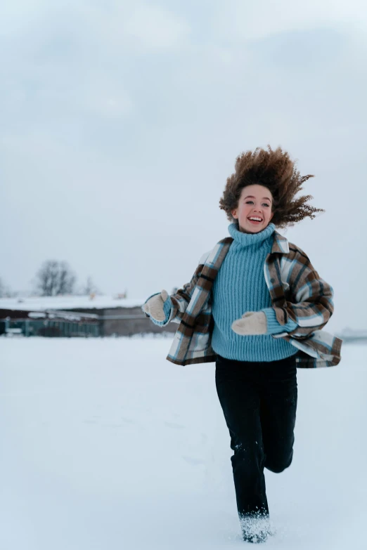 a girl is laughing while jumping in the snow
