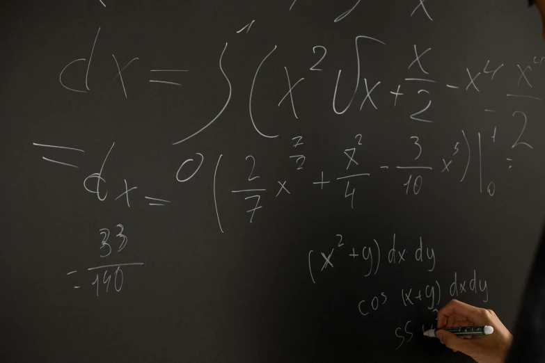 a man writing on a blackboard with lots of writing