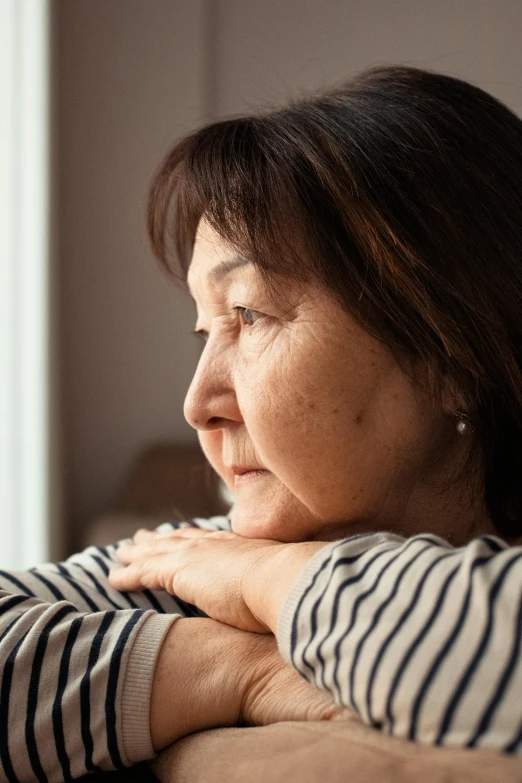 an old woman looks to the side while leaning her head on her arm