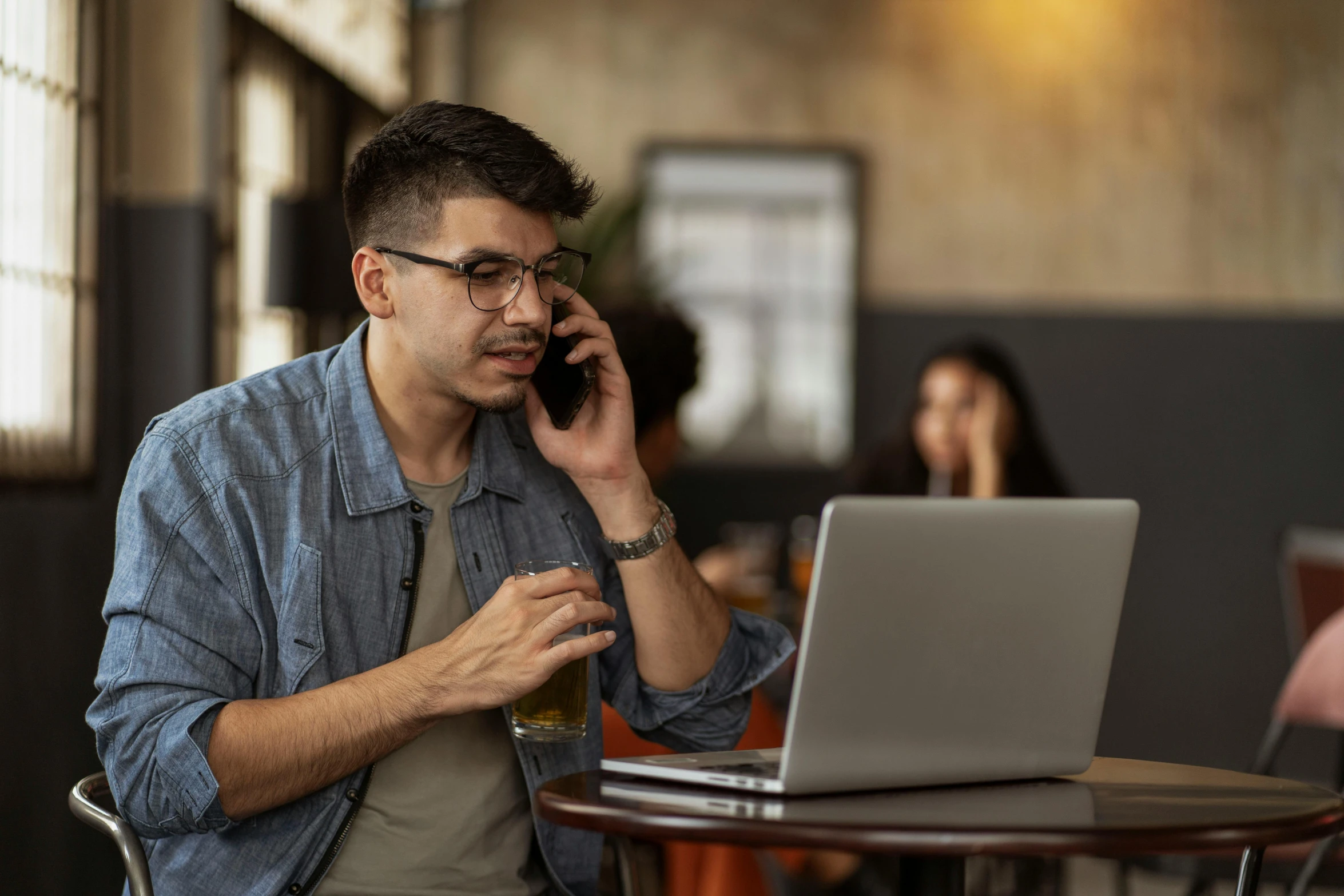 a man talking on the phone while using a laptop