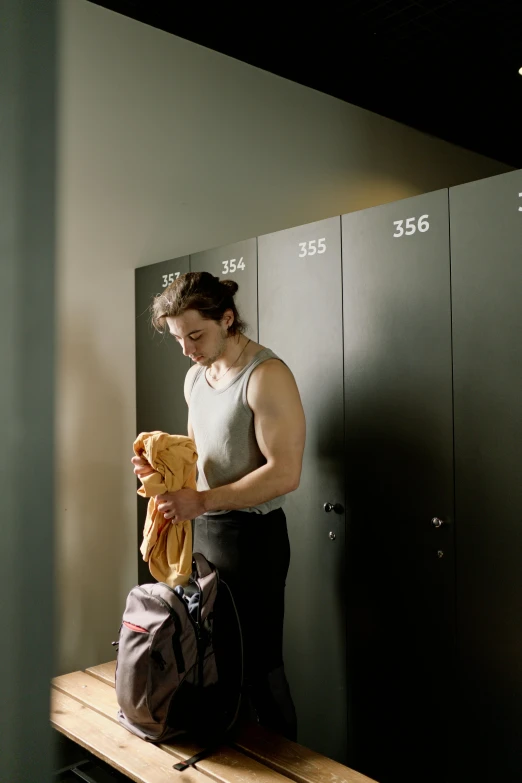 the man is standing on the bench by his locker