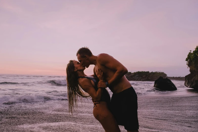 a man and a woman standing on top of a beach