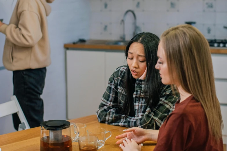 three girls are around a table with cups and a pitcher