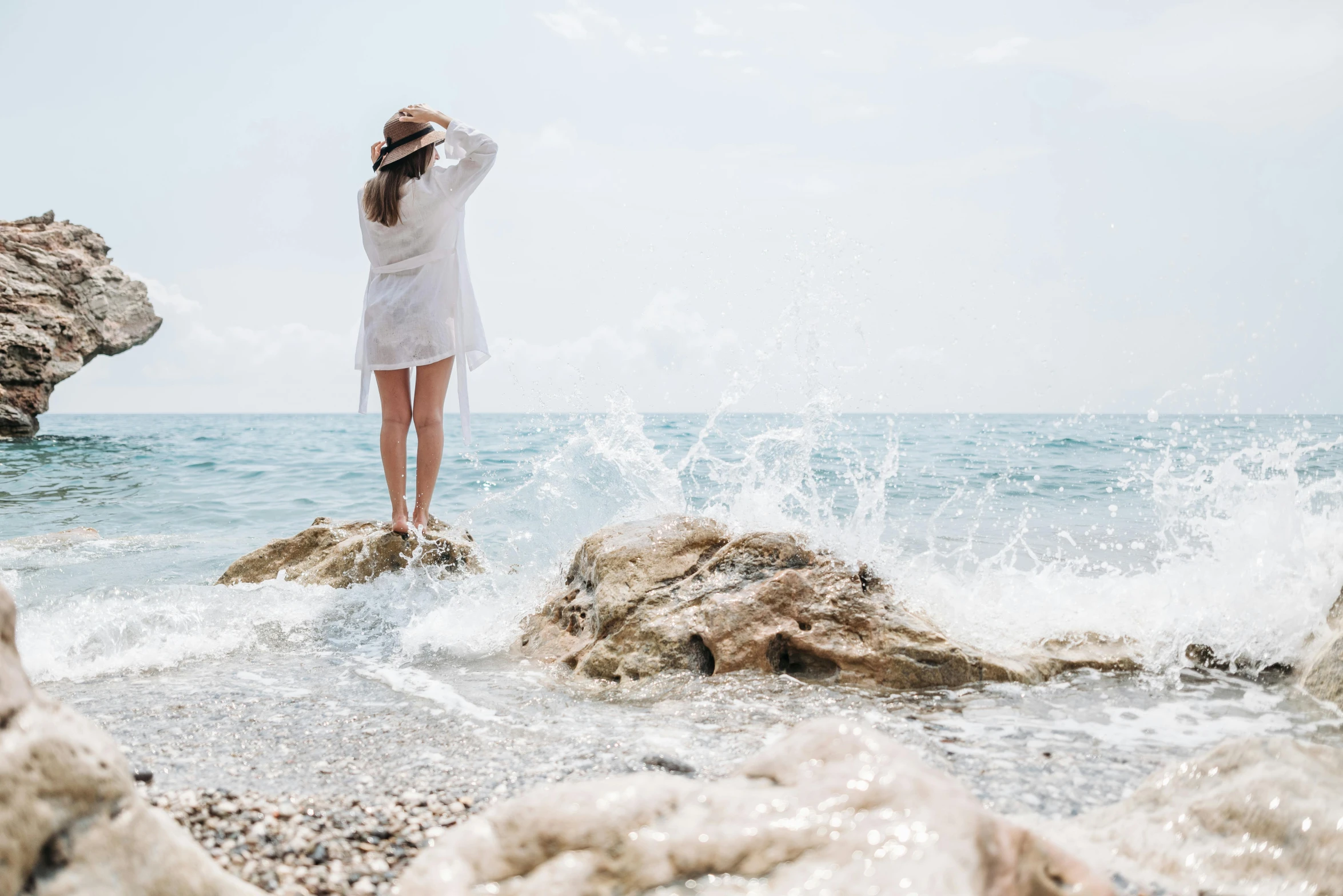 a woman standing on rocks in the ocean waves