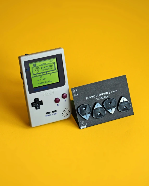 a compact gameboy next to a matching business card on a yellow background