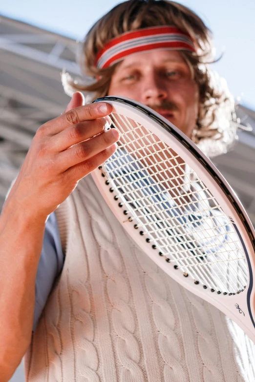 a man wearing white holds his tennis racket up