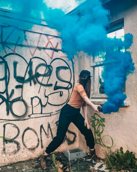 a girl standing next to a wall covered in blue smoke