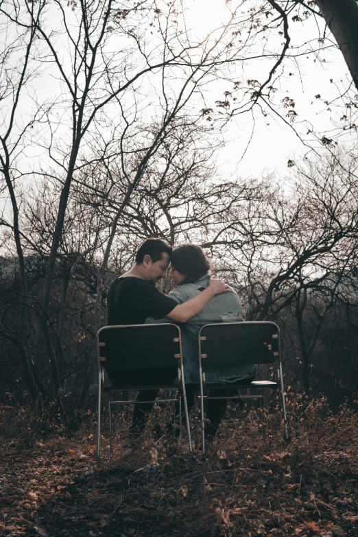 two people sitting on an outdoor bench facing the camera