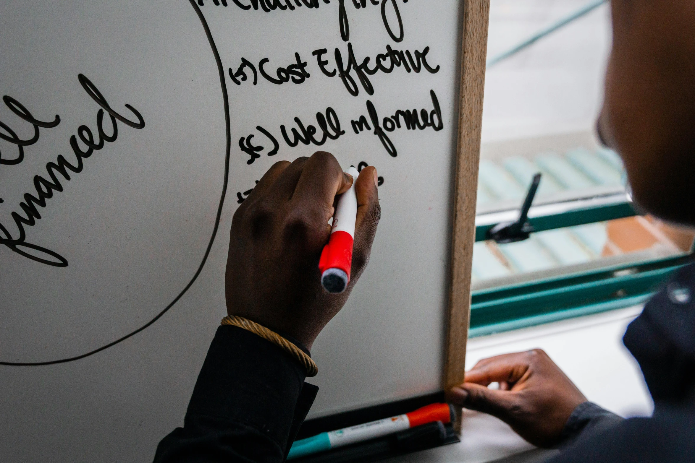 a man writing on a white board with marker