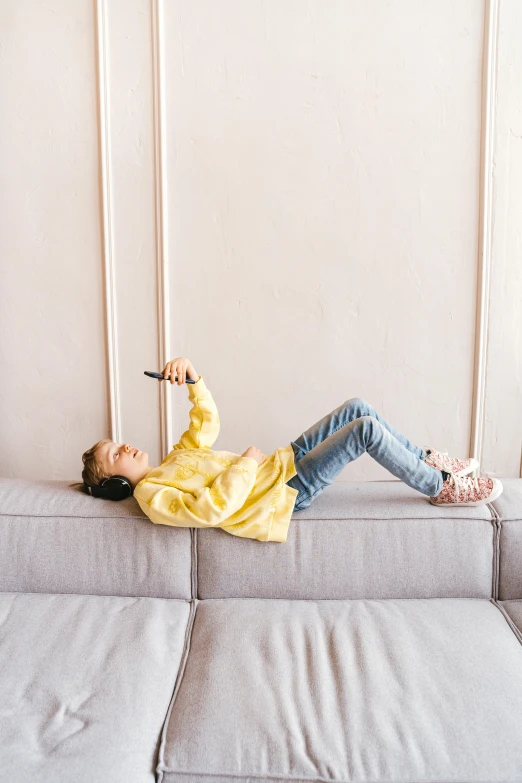 a woman laying on top of a gray couch