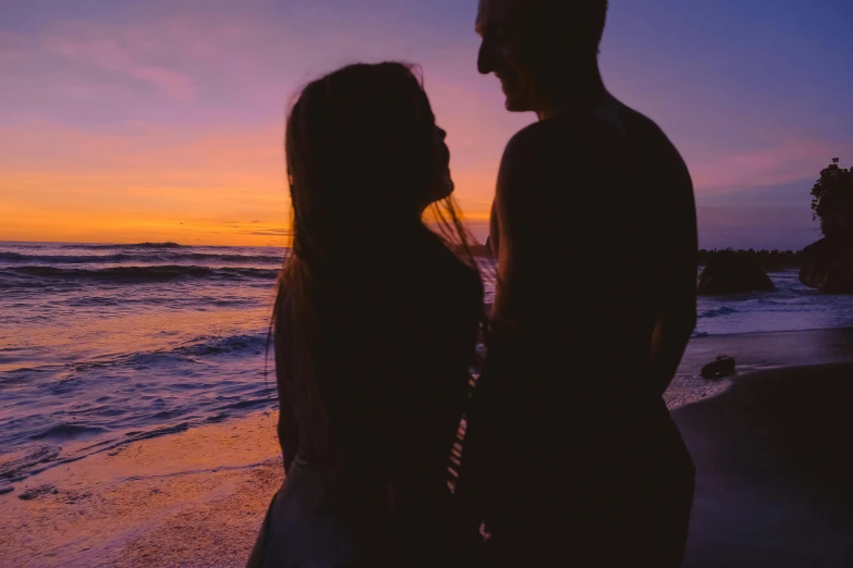 two people stand next to each other at the beach