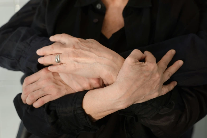 two older people's hands with a wedding ring on top of their thumb