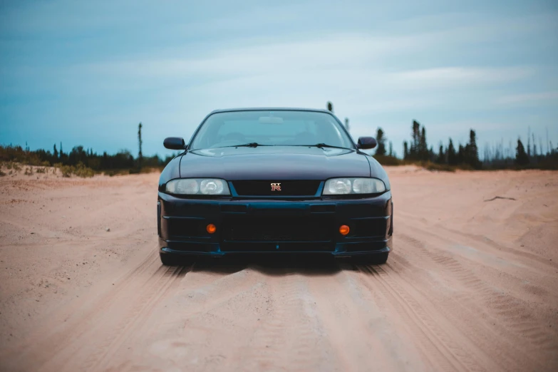 a blue car parked in the dirt on a street