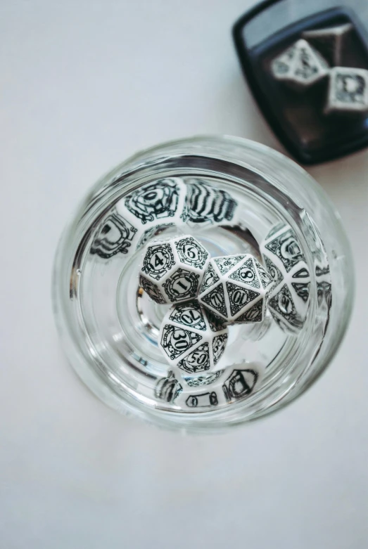 a glass with silver dices and numbers inside