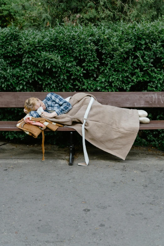 the woman is lying on the bench outside