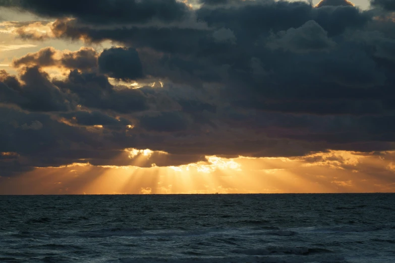 the sun is shining through clouds over the water