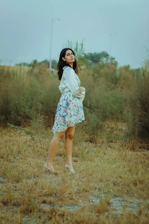 a woman in a dress is standing in a field