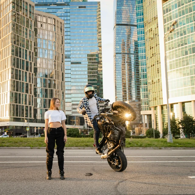 two people with motorcycles and some large buildings