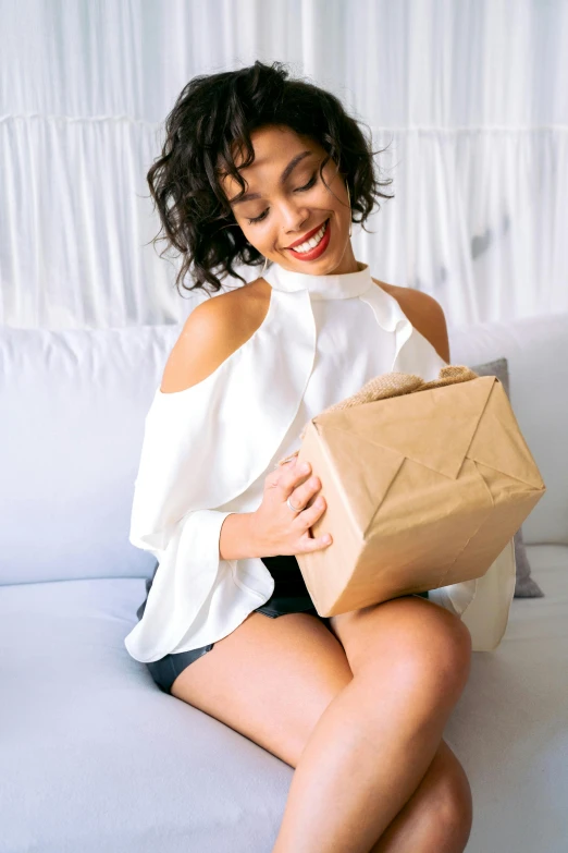 a woman sits holding a brown bag in one leg and sitting on the ground