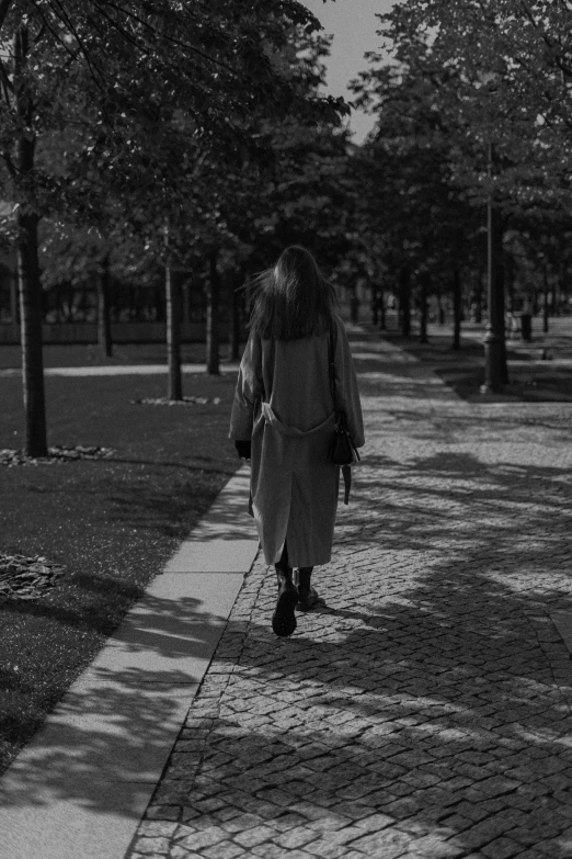 a black and white po of a woman walking on a sidewalk