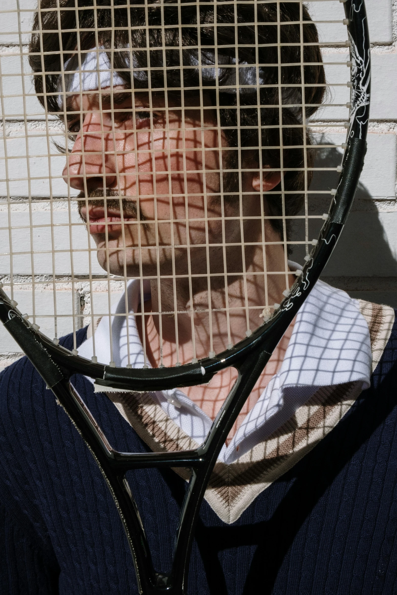 man with tennis racket looking through large cage