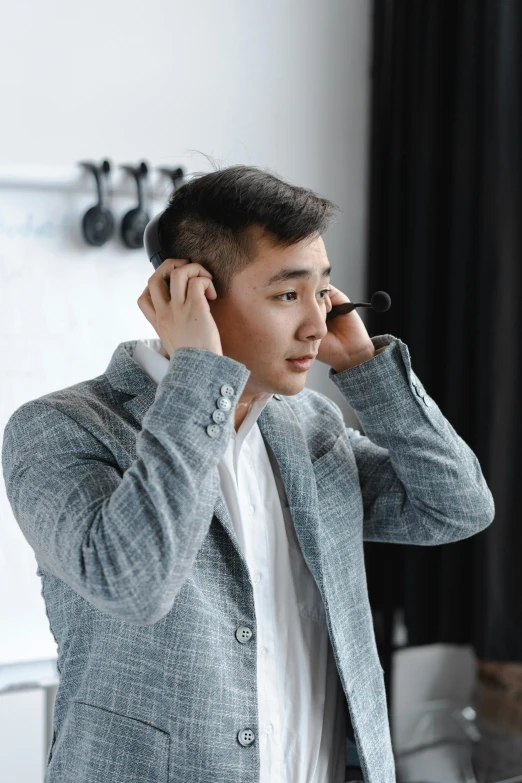 a young man wearing a jacket, holding a cell phone to his ear