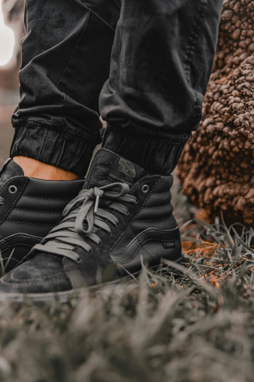 a person in black sneakers standing on some grass