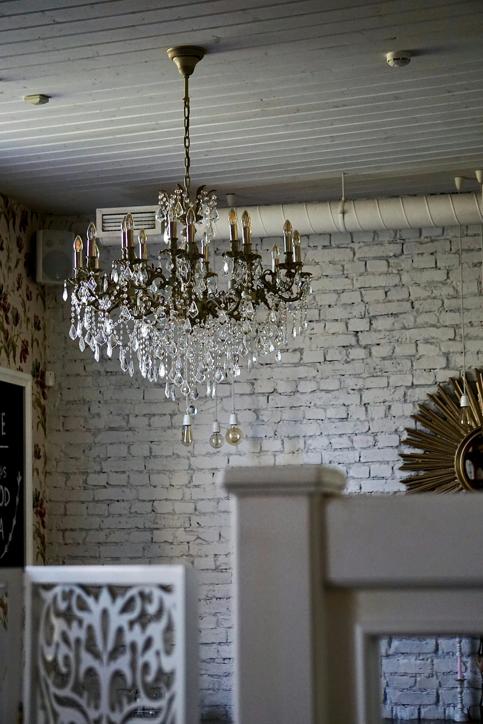 the room with a white brick wall and crystal chandelier