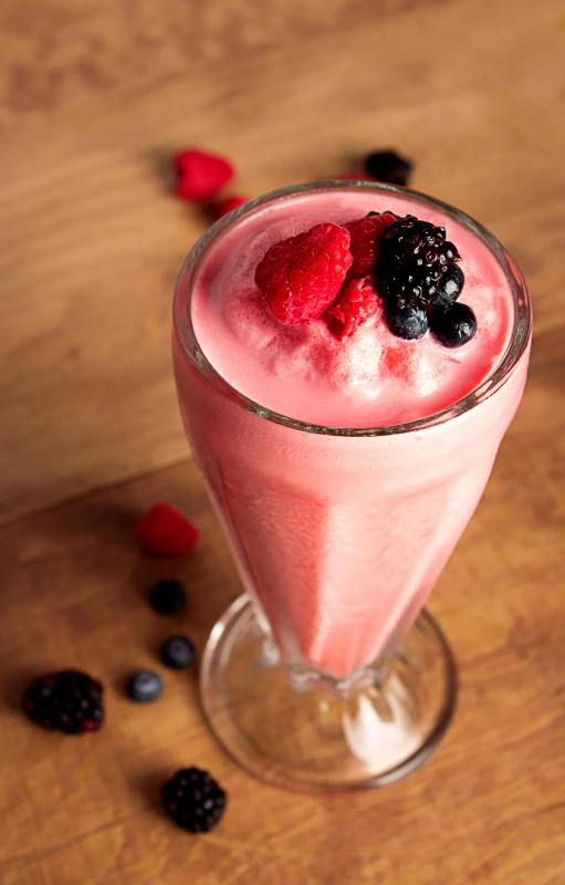 a smoothie garnished with raspberries and blackberries is sitting on a table