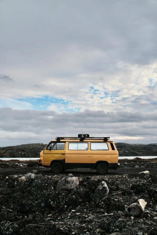 an old school van sits parked on the beach near water