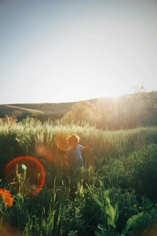 a boy is playing in the grass with an orange frisbee