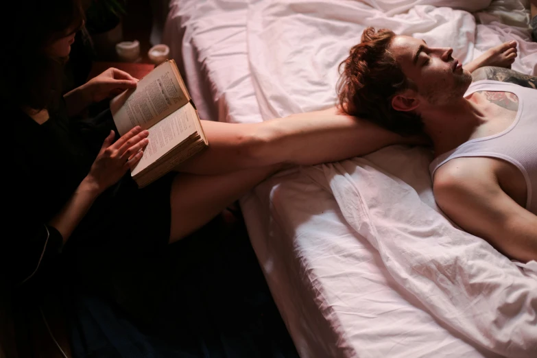 a man laying on a bed with an open book