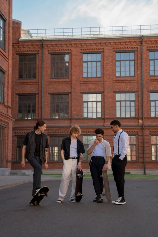 a group of young men holding skateboards next to an industrial building