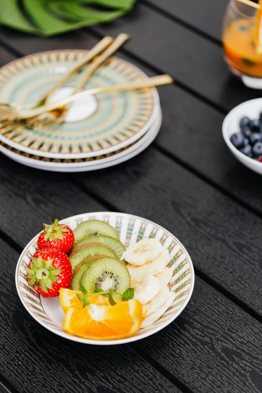 plate of fruit and strawberries sitting on table outdoors