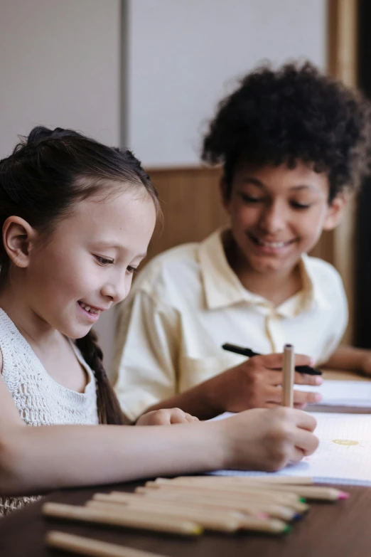 two s sitting at a table and working on paper