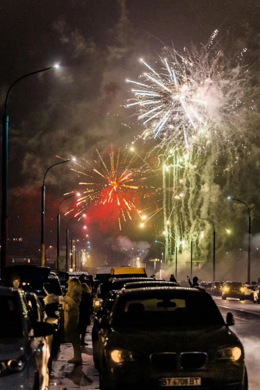 firework display in the sky over a street and cars