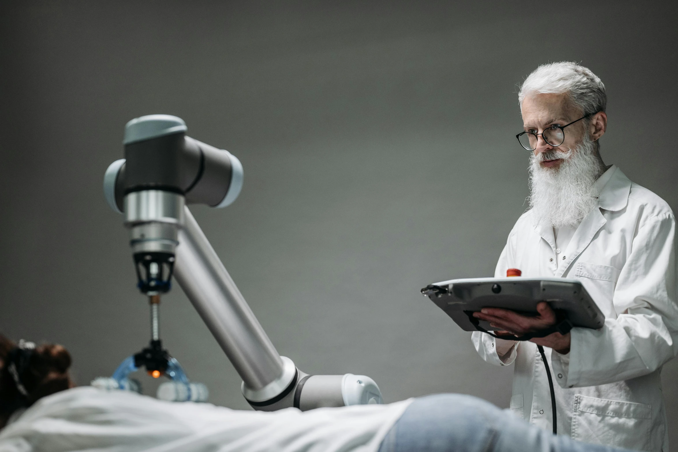 the scientist holds an ipad while looking at the robot