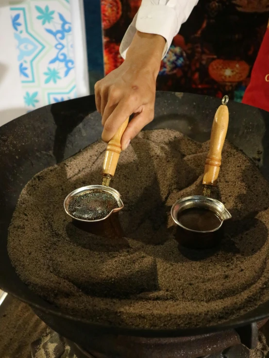 a person scooping spices into a pot and spoon